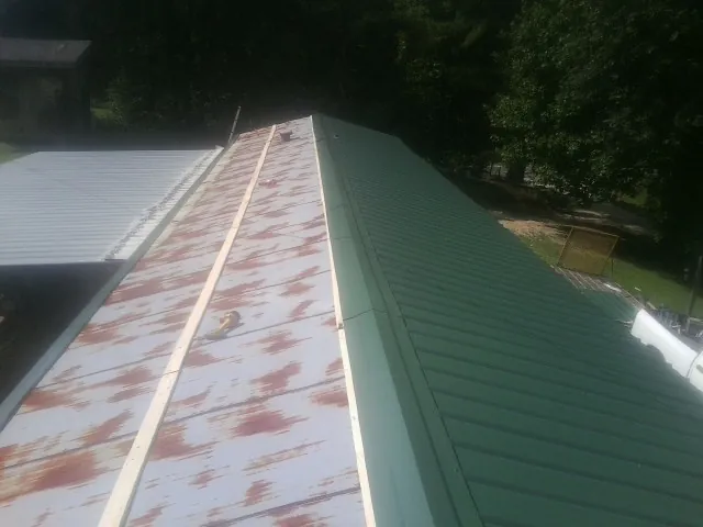 Old rusted panels beside newly installed green metal roofing — Wind Damage Roof Repair by Roofing Brothers in Sheridan