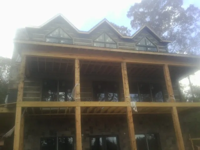 Dormers and porch framing on a large log home under construction — Roof Coating work by our crew in Sheridan